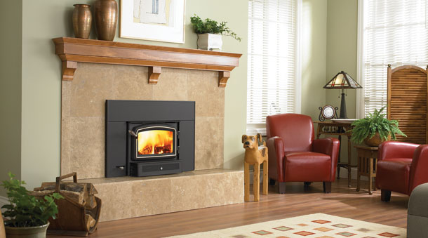 Regency Fireplace insert in black with brown stone surround and two leather chairs and lamp to the right.