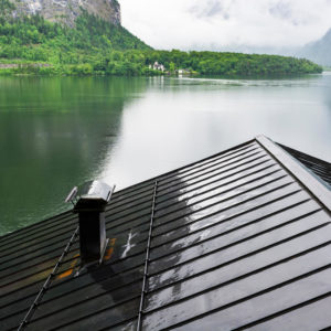 wet roof with chimney in front of a lake during rainy weather