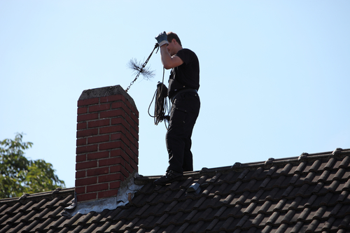 Chimney sweep inserting a brush chimney sweep on roof